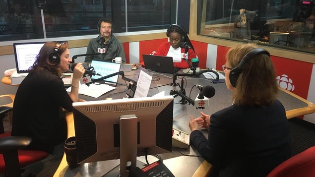 Une femme et trois hommes sont assis autour d'une table dans un studio de radio
