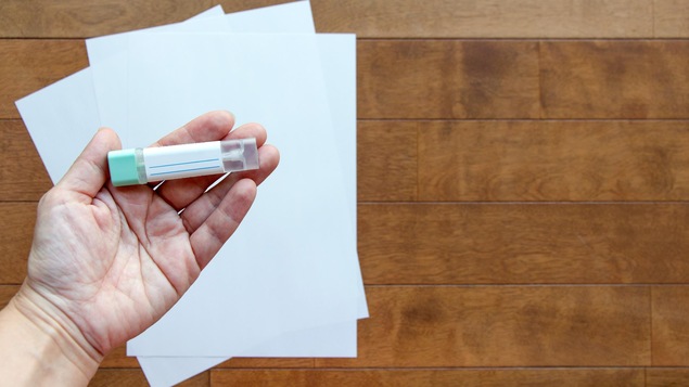 Une main tient un petit étui de plastique dans lequel se trouve un bandelette.