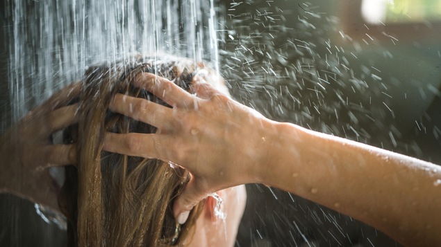Close up of a woman washing her hair while showering in the morning.