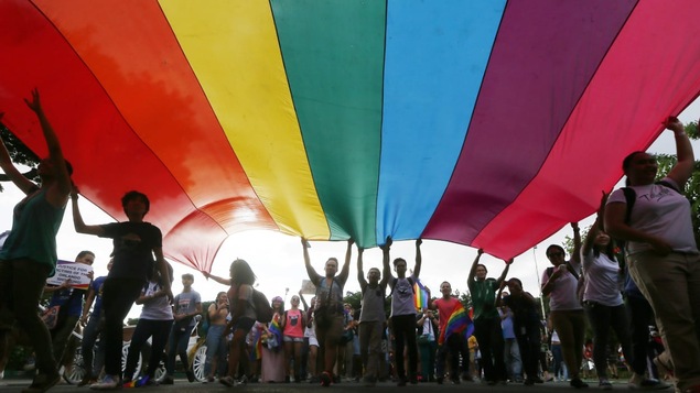 Des jeunes brandissant une bannière arc-en-ciel