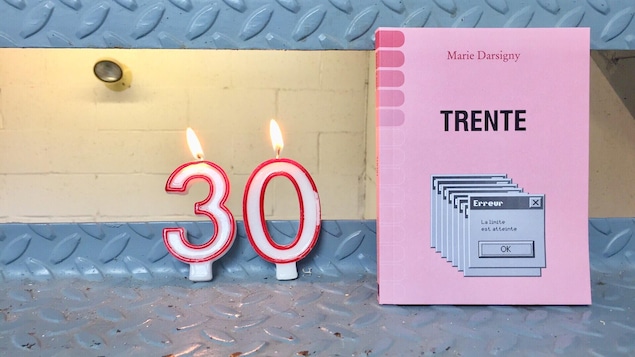Une bougie allumée qui indique 30 ans et un livre rose.