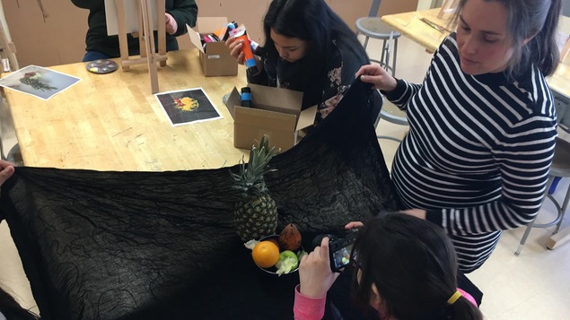 Une élève prend en photo la nature morte qu'elle souhaite peindre