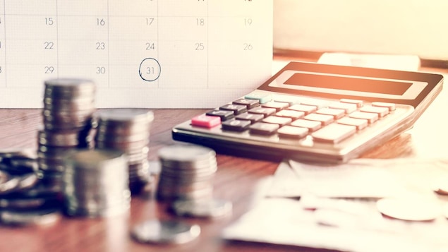 Un calendrier, de la monnaie et une calculatrice sont placés sur une table.