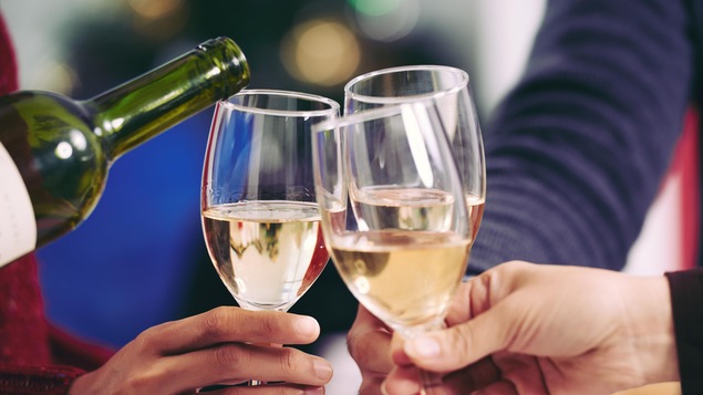 Des gens célèbrent le Nouvel An avec des coupes de vin blanc.