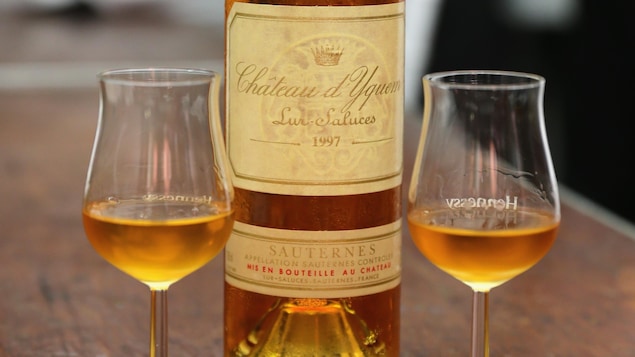 Une bouteille de vin doré entourée de deux verres.