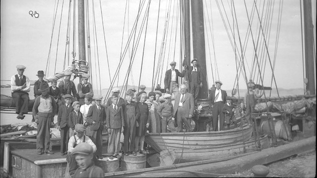 Des Madelinots posant devant les bateaux qui les mèneront vers l'Abitibi en 1942.