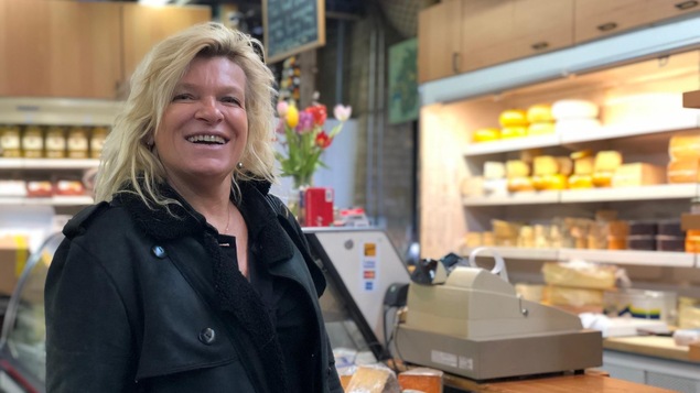 La chef française Flora Mikula debout devant un étalage de fromages