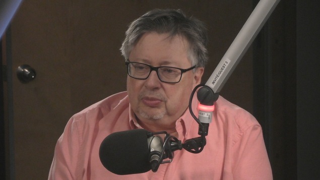 Yves Frenette est assis en studio radio derrière un microphone