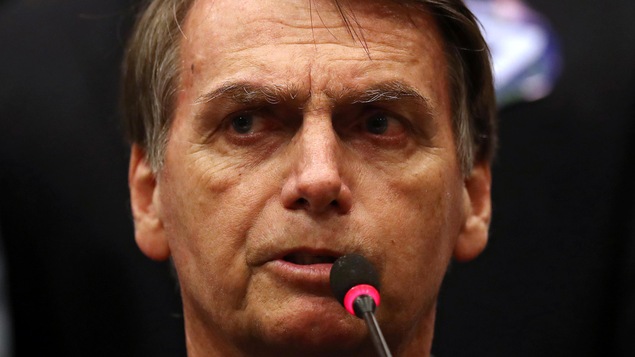 Portrait de Jair Bolsonaro devant un micro.