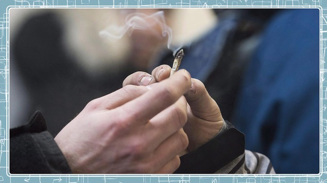 En gros plan, une main qui donne une cigarette de cannabis à une autre main.