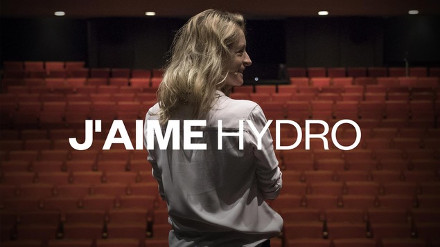La comédienne souriant face aux sièges vides d'une salle de spectacle.