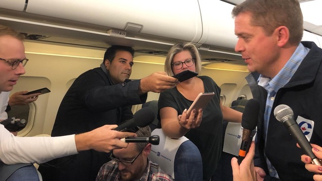 À bord d'un avion, les journalistes Louis Blouin, Omar Sachedina, Bryan Mullan et Katie Simpson posent des questions à Andrew Scheer.