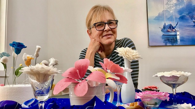 Une femme assise devant des fleurs en sucre de différentes couleurs