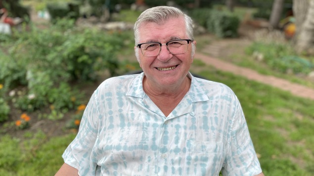 Michael Sovyn a un grand sourire et il porte des lunettes.