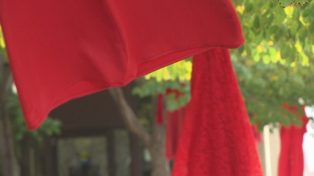 Des robes rouges accrochées à des arbres flottent dans le vent.