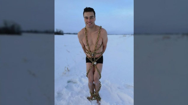 Roger Boucher en maillot de bain, debout et enchaîné, dans la neige.