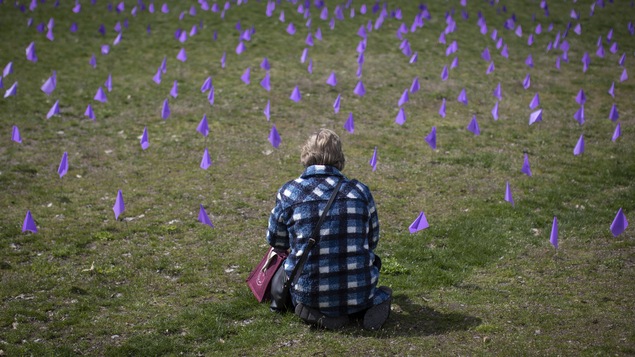 Une personne est assise au milieu de petits drapeaux violets. 