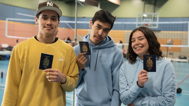 Les trois jeunes tiennent en main leur passeport. 