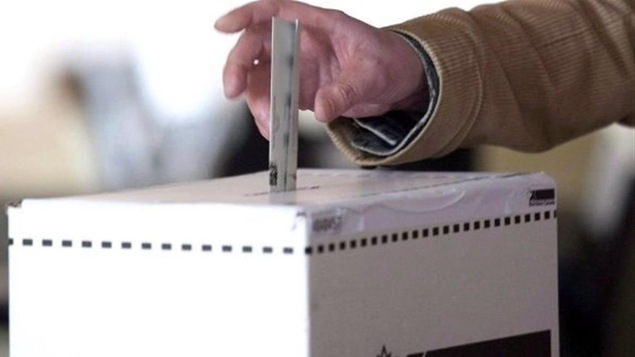 Un bulletin de vote qui est déposé dans une boite de scrutin