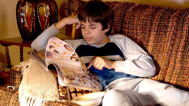 Un garçon en pyjama, sur un sofa, lit un catalogue. Un garçon en pyjama, sur un sofa, lit un catalogue.
