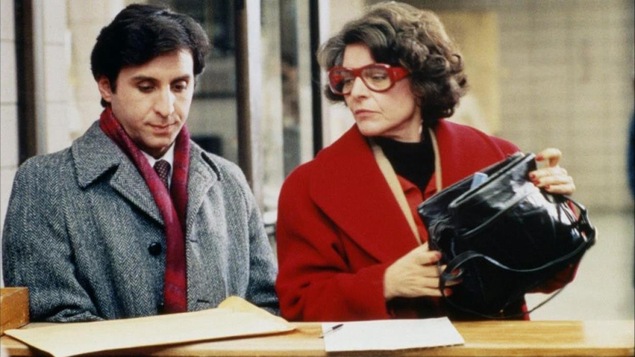 Une femme portant lunettes et manteau rouge à côté d'un homme plus jeune, en pardessus gris. Une femme portant lunettes et manteau rouge à côté d'un homme plus jeune, en pardessus gris.