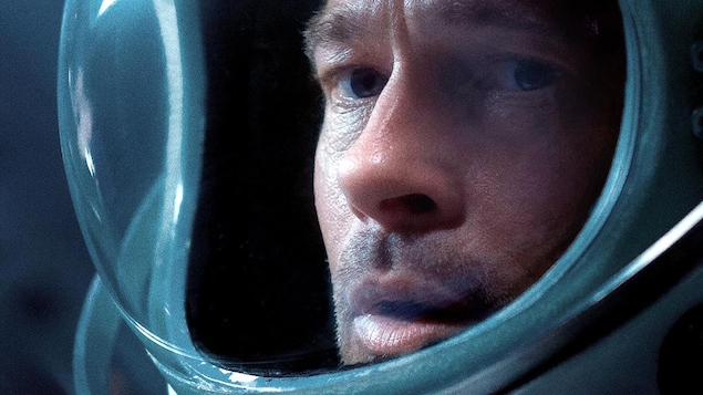 Un homme (Brad Pitt) portant un casque de cosmonaute en très gros plan. Un homme (Brad Pitt) portant un casque de cosmonaute en très gros plan.