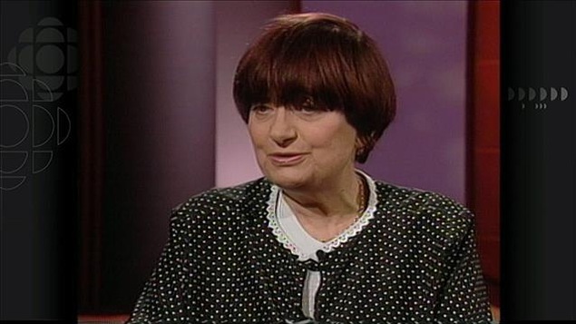 Une femme (Agnès Varda) en plan moyen devant un fond violet. Une femme (Agnès Varda) en plan moyen devant un fond violet.