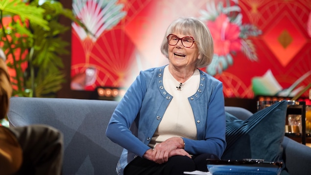 La femme est assis sur un divan dans un studio de télévision et elle rit. La femme est assis sur un divan dans un studio de télévision et elle rit.