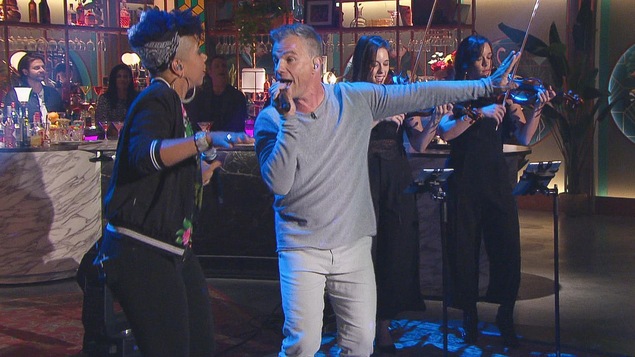 Il chante. Il porte un chandail et un pantalon gris. Il chante. Il porte un chandail et un pantalon gris.