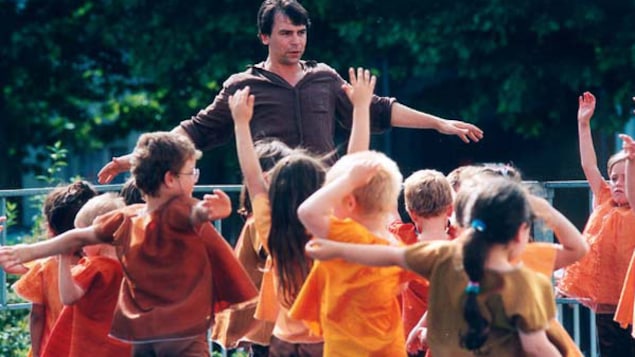 Un homme devant des enfants, qui dansent.