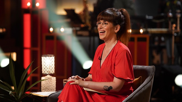 La femme habillée d'une robe rouge est assise dans un fauteuil dans un studio de télévision et elle rit. La femme habillée d'une robe rouge est assise dans un fauteuil dans un studio de télévision et elle rit.