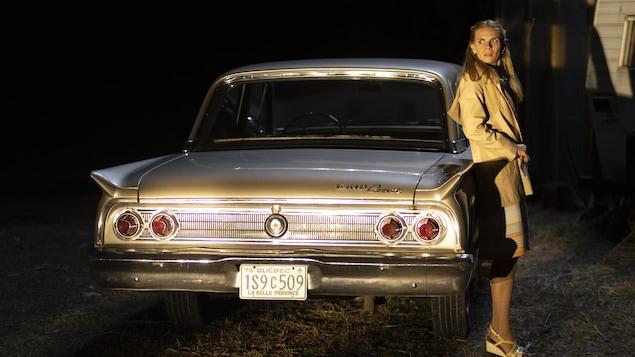 Huguette (Marilyn Castonguay) se tient debout à côté de sa voiture.