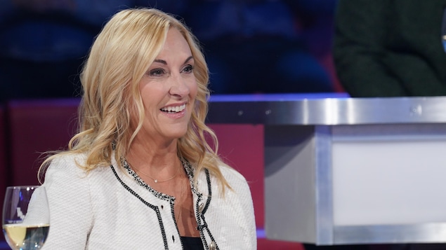 Une femme aux cheveux blonds. Elle porte une veste blanche. Une femme aux cheveux blonds. Elle porte une veste blanche.