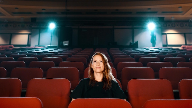Une femme (Karine Vanasse) assise seule au milieu d'une salle de cinéma.