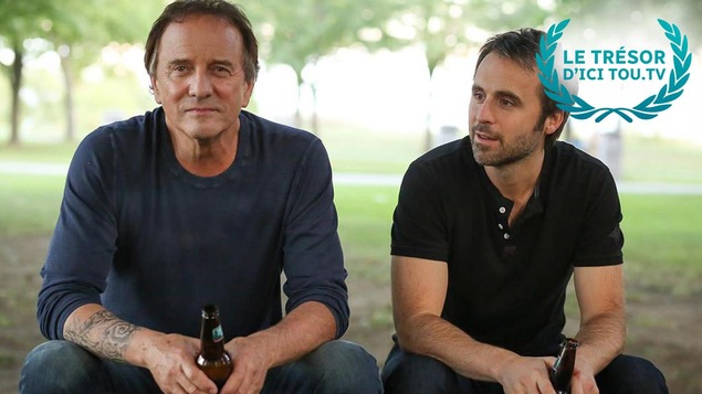 Deux hommes (Michel Côté et Louis-José Houde) assis côte à côte et sur la photo la mention Le trésor d'ICI Tou.tv. Deux hommes (Michel Côté et Louis-José Houde) assis côte à côte et sur la photo la mention Le trésor d'ICI Tou.tv.