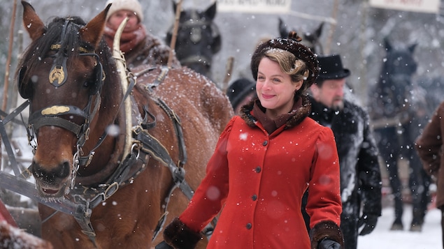 Elle est dehors en plein hiver avec un cheval et un joli manteau rouge. Elle est dehors en plein hiver avec un cheval et un joli manteau rouge.
