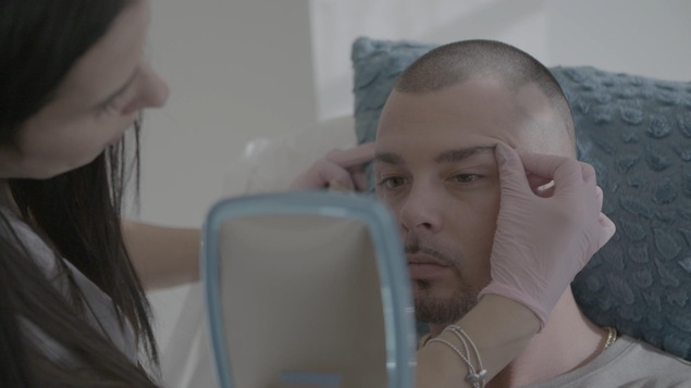 Un jeune homme se fait remonter les sourcils en se regardant dans le miroir. Un jeune homme se fait remonter les sourcils en se regardant dans le miroir.