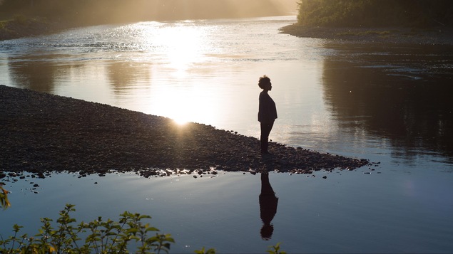 Sur le bord d'une rivière, une femme regarde au loin. Sur le bord d'une rivière, une femme regarde au loin.