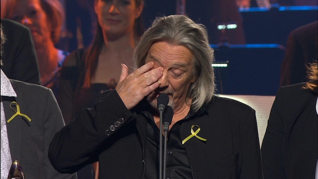 Sur scène, il essuie une larme suite à l'hommage que son groupe a reçu. Sur scène, il essuie une larme suite à l'hommage que son groupe a reçu.
