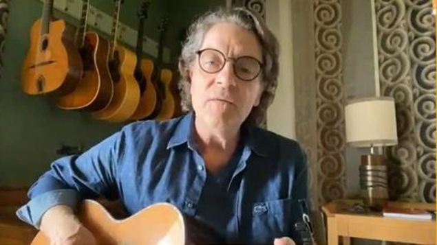 Il est en vidéoconférence, une guitare à la main, dans une pièce de sa maison. Il est en vidéoconférence, une guitare à la main, dans une pièce de sa maison.