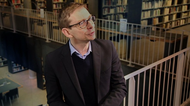 Un homme debout dans une bibliothèque.