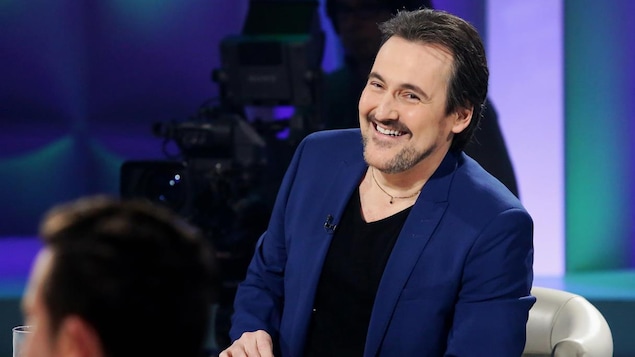 Guy porte un chandail noir à col en v et un veston bleu royal.