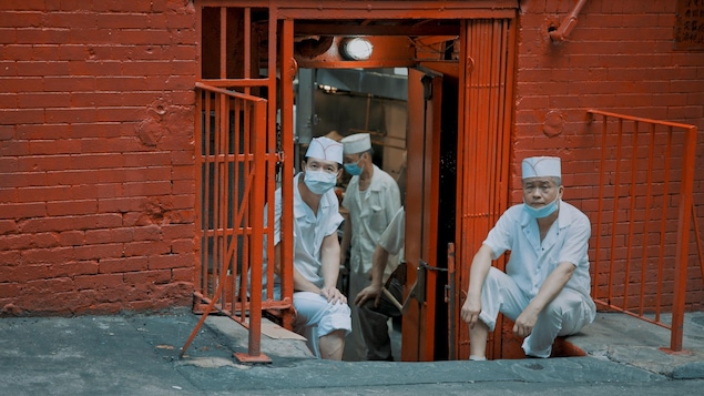 Deux hommes qui travaillent dans un restaurant sont assis à la porte l'établissement.