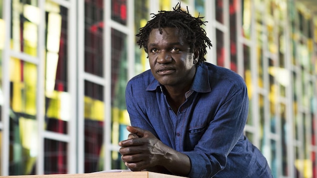 Boucar Diouf est accoter sur un meuble dans une bibliothèque et regarde droit devant lui. Boucar Diouf est accoter sur un meuble dans une bibliothèque et regarde droit devant lui.