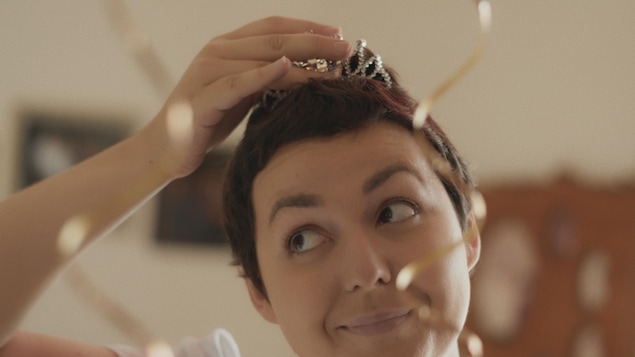Une jeune femme place une couronne sur ses cheveux courts. Une jeune femme place une couronne sur ses cheveux courts.