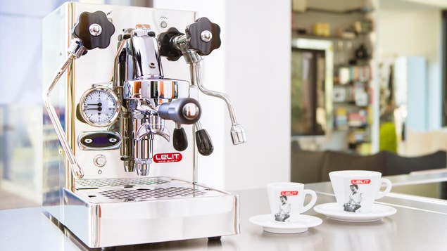Machine à café espresso en acier sur comptoir à côtÉ de deux tasses à café blanche.