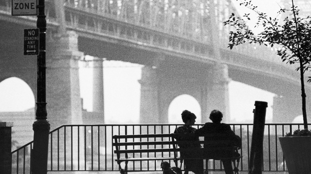 En noir et blanc, un homme et une femme de dos, assis sur un banc, sous le pont de Brooklyn, à New York. En noir et blanc, un homme et une femme de dos, assis sur un banc, sous le pont de Brooklyn, à New York.