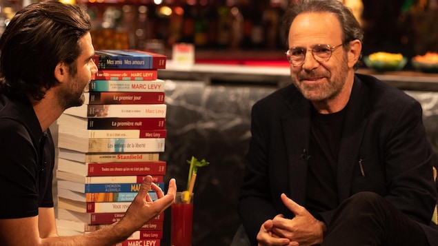 Les deux hommes sont face à face avec une pile de livres entre eux. Les deux hommes sont face à face avec une pile de livres entre eux.
