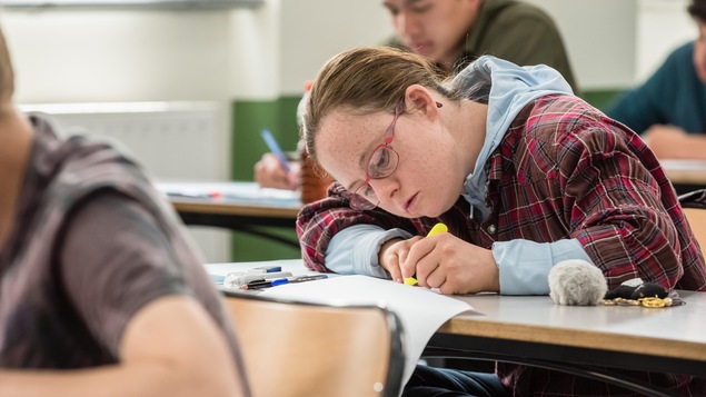 Une jeune fille, portant des lunettes, en train de passer un examen en classe. Une jeune fille, portant des lunettes, en train de passer un examen en classe.