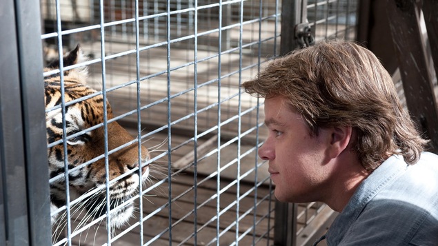 Un homme face à un tigre dans une cage.
Un homme face à un tigre dans une cage.